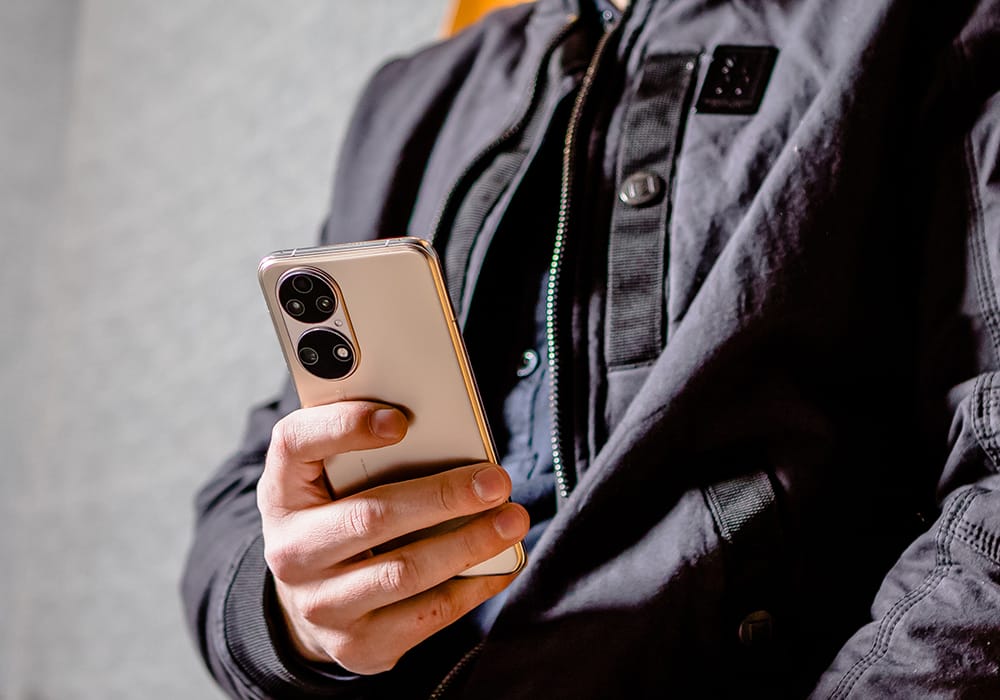 HUAWEI P50 - Lifestyle - Image of a person wearing black clothing holding a gold Huawei P50 in their hand
